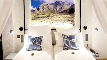 Una habitación con dos camas, un ventanal con vistas a la montaña y un teléfono en la pared.