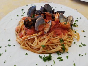 A plate of spaghetti with clams and shrimp, garnished with parsley. - Parco della Vigna (Martina Franca)