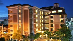 A multi-story hotel with a central courtyard, balconies, and a parking area. - Grand Marina Residence (Si Racha)