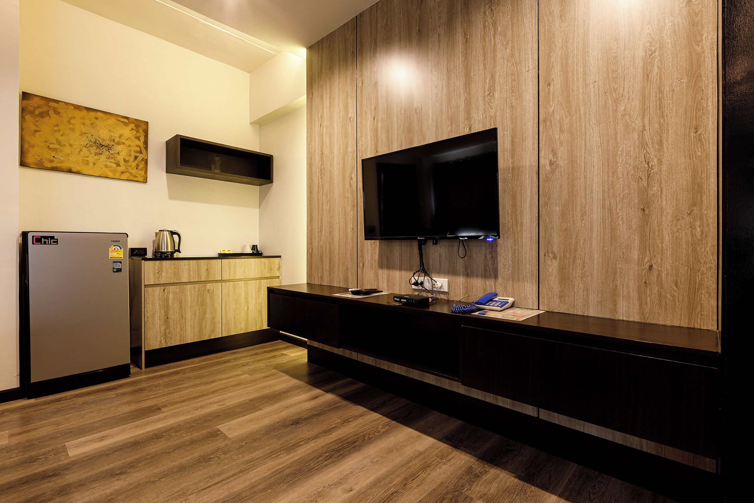 Una cocina moderna con refrigerador integrado, armarios de madera, un televisor de pantalla plana en la pared y una cafetera sobre la encimera.