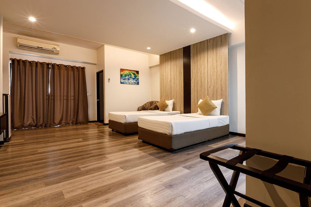 Une chambre d’hôtel avec deux lits, un plancher en bois, un appareil de climatisation, un tableau et un bureau.