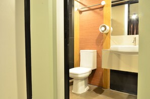 Une salle de bain moderne avec des toilettes blanches, des éléments décoratifs en bois et un miroir au-dessus du lavabo.