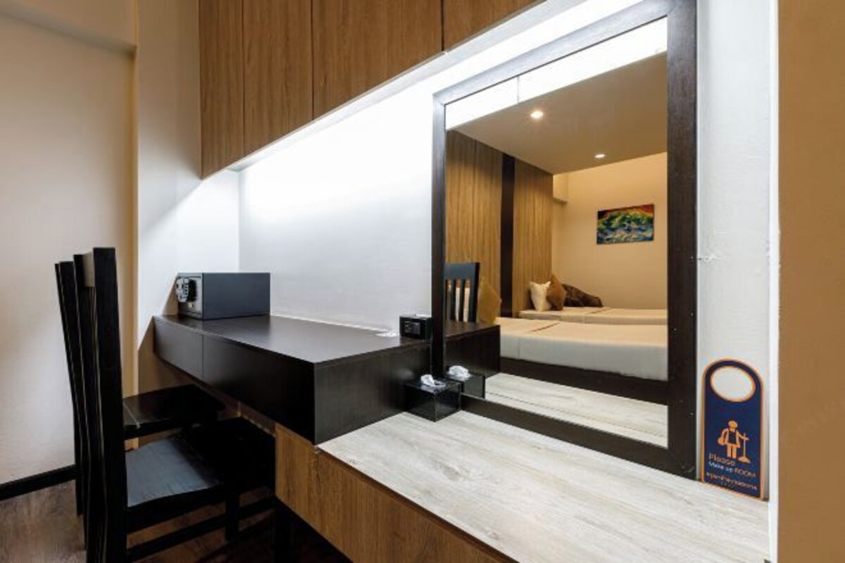 Una habitación de hotel moderna con un escritorio de madera, un espejo y una cama con un cuadro en la pared.