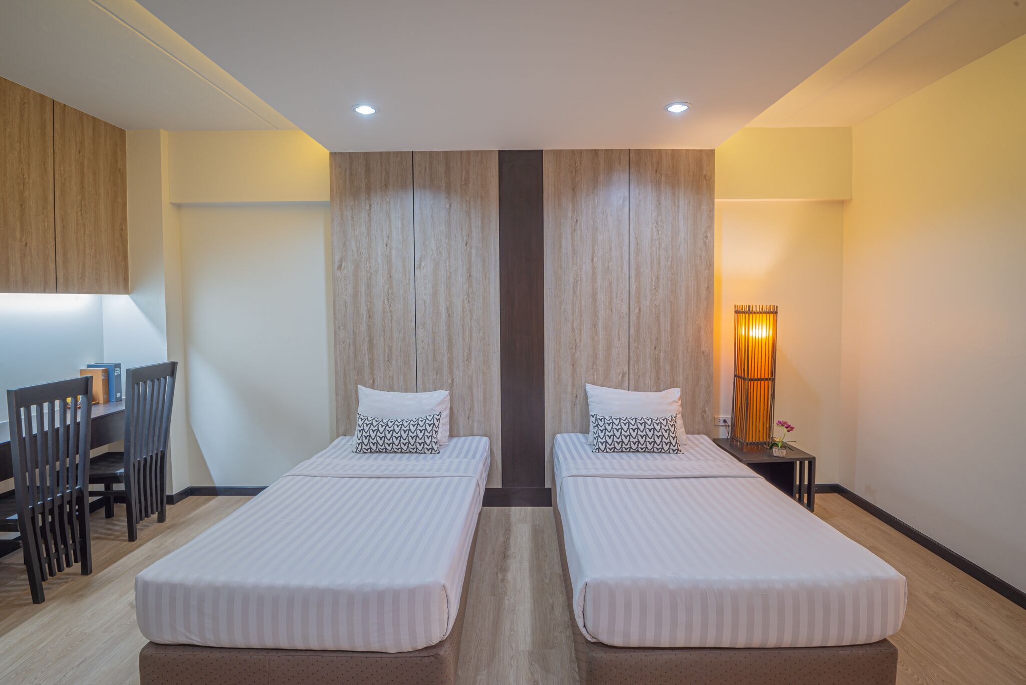 A hotel room with two single beds, a desk, and a chair.