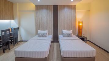 A hotel room with two single beds, a desk, and a chair.