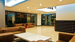 A modern lobby with leather sofas, a white coffee table, and a glass partition. - Grand Marina Residence (Si Racha)