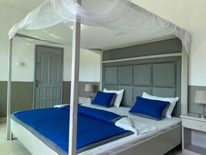 A bedroom with a four-poster bed, a grey headboard, and a canopy. - Pelican Residence (Bakau)