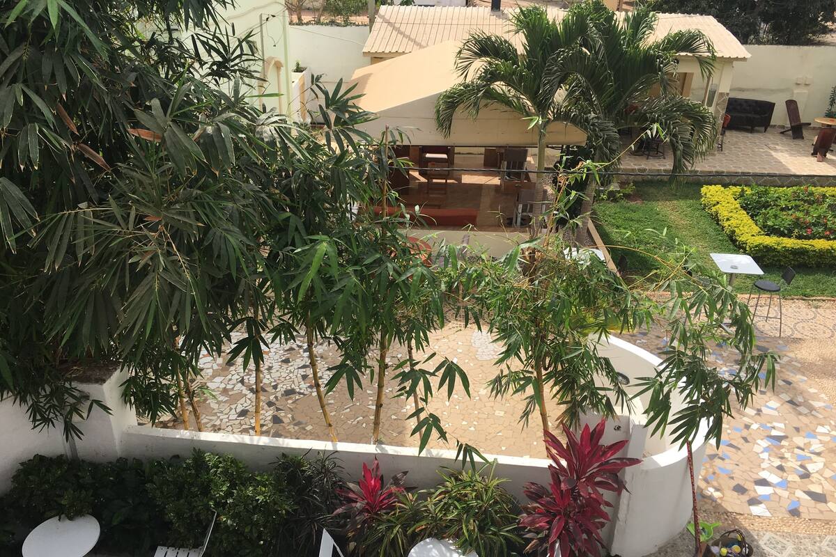 An outdoor patio area with a tiled floor, several potted plants, and white folding chairs.