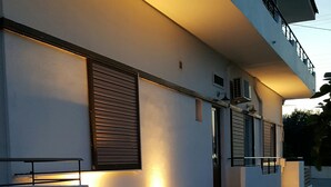 A modern building with a flat roof, large windows, and a balcony. - Koukounari Rooms (Agistri)
