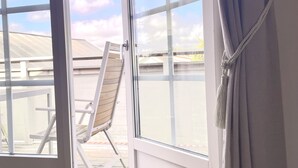 Une pièce dotée d’une porte-fenêtre coulissante donnant sur une terrasse extérieure avec un fauteuil.