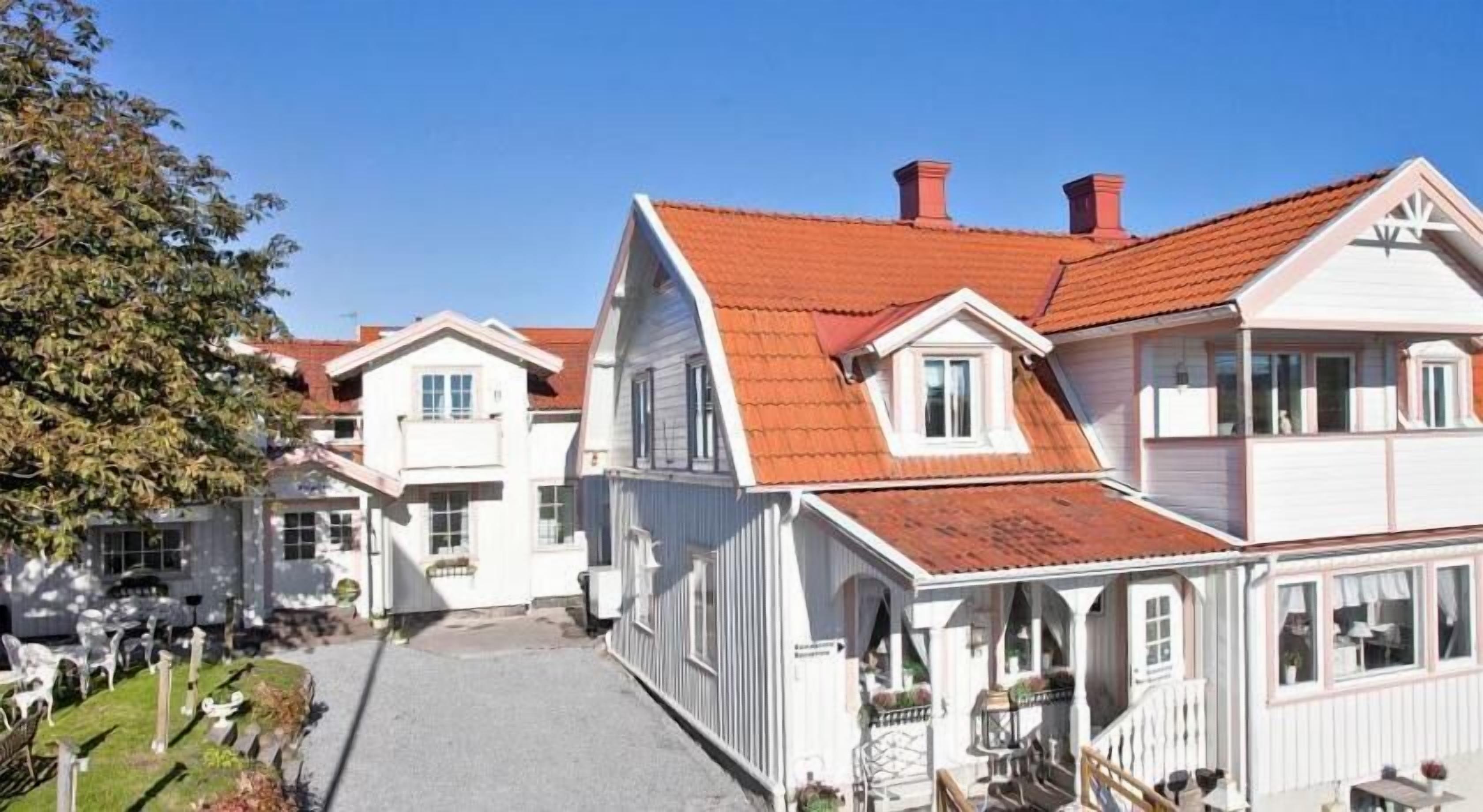 A row of white buildings with red roofs and a paved driveway.