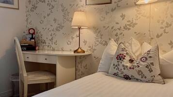 A neatly arranged bedroom with a bed, a desk, and a chair.