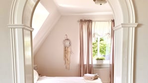 Une chambre à coucher avec un lit, un attrape-rêves et une fenêtre avec des rideaux.