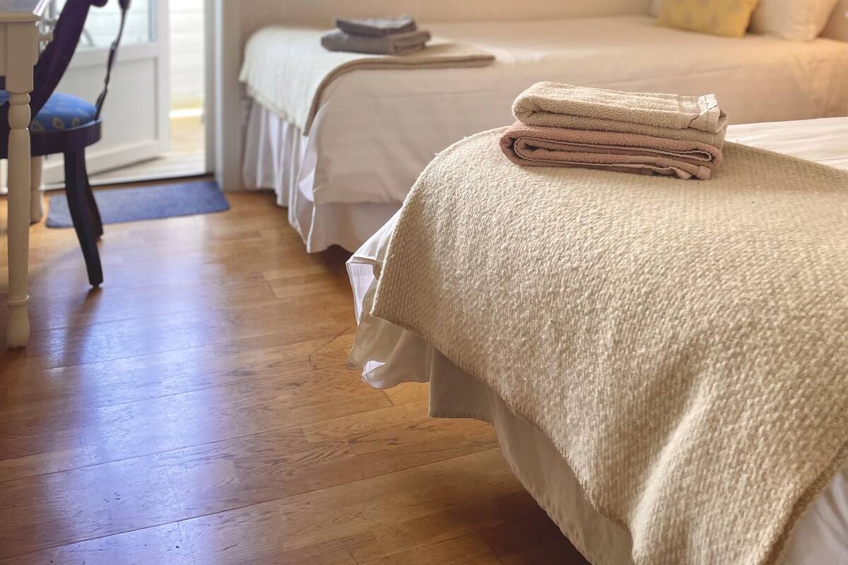 Une chambre à coucher avec un lit, une chaise, un bureau et une fenêtre avec des rideaux.