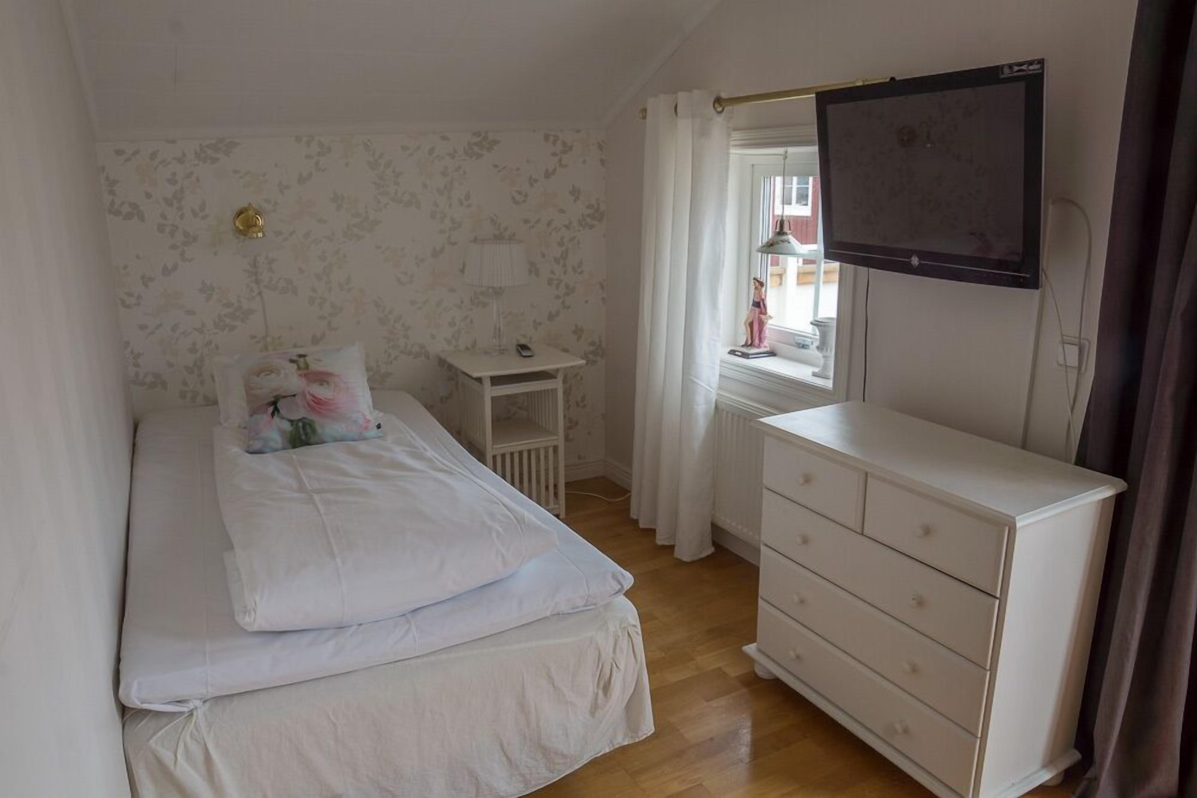 A bedroom with a bed, dresser, and a TV mounted on the wall.