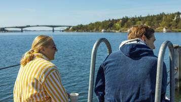 Two individuals seated by a body of water with a bridge in the background.
