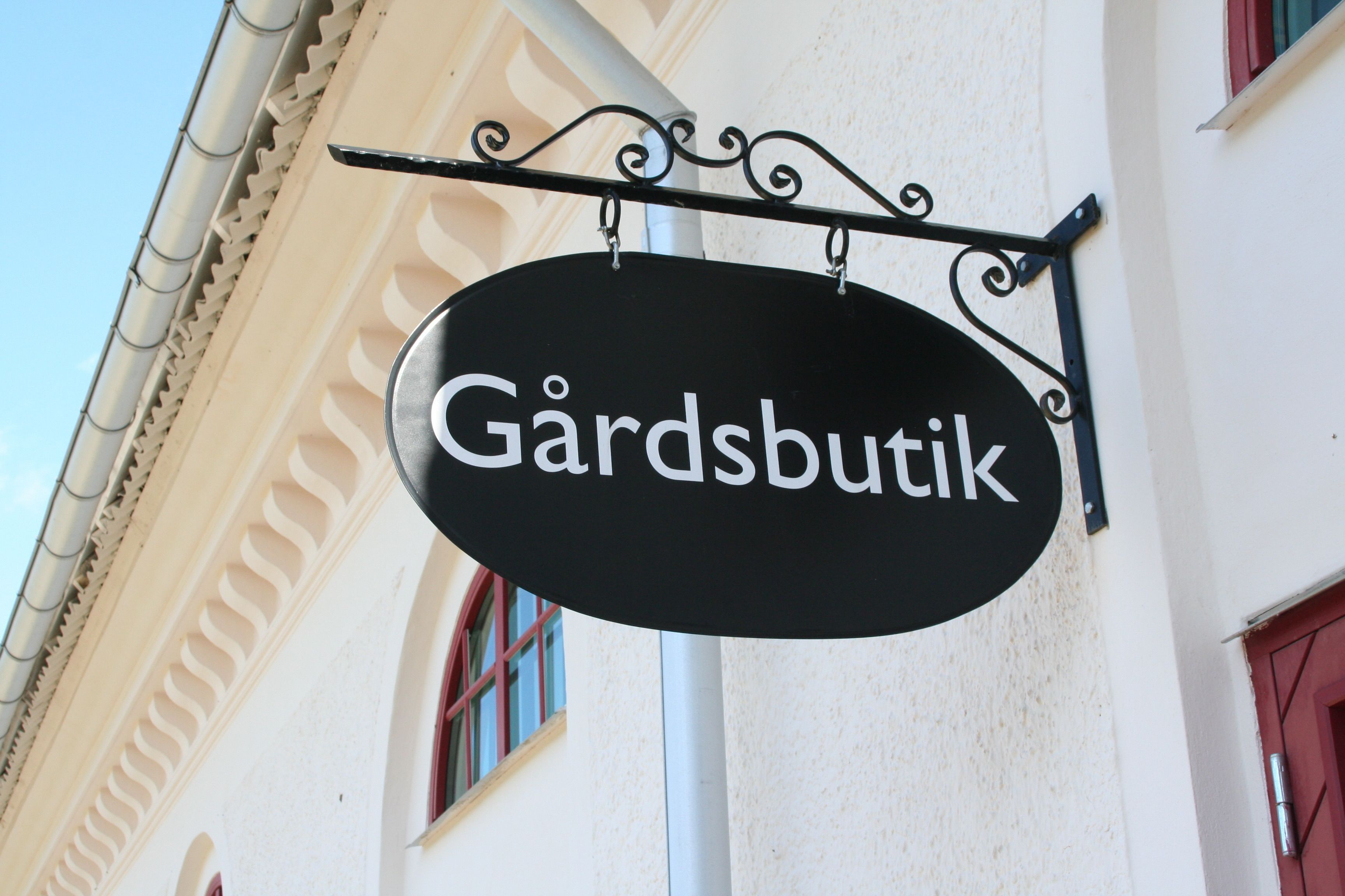A sign with the name "Gärdsbutik" hanging from a building.