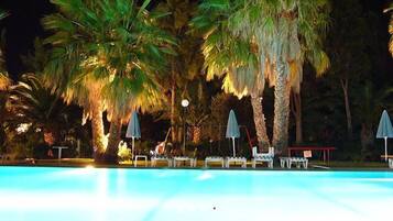 Een buitenzwembad, parasols bij het zwembad en ligstoelen