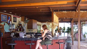 A bar area with a counter, stools, and a person sitting. - Nina Beach Hotel (Kos)