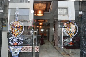 L'entrée d'un hôtel, avec des portes en verre richement décorées de motifs complexes.