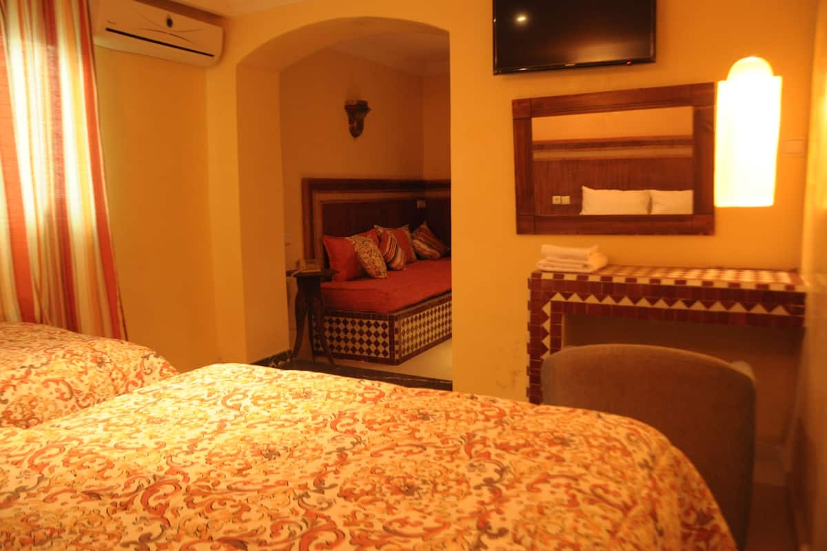 A hotel room with two beds, a television, a mirror, and a small table with a towel.
