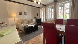 A living room with a sofa, a table, chairs, a lamp, and a suitcase. - Urlaub im Fachwerk (Quedlinburg)