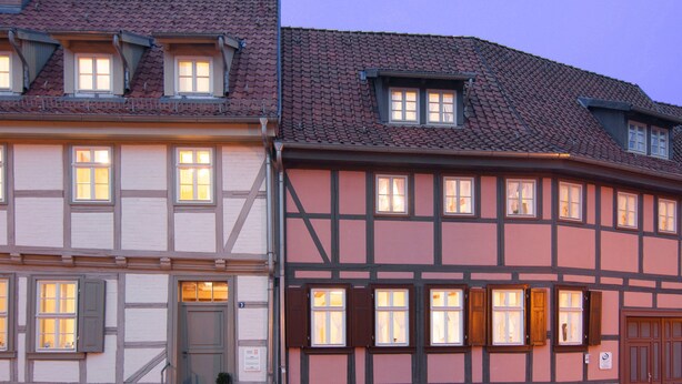 A traditional half-timbered building with multiple windows and a door, featuring a stone base and a tiled roof. - Urlaub im Fachwerk (Quedlinburg)