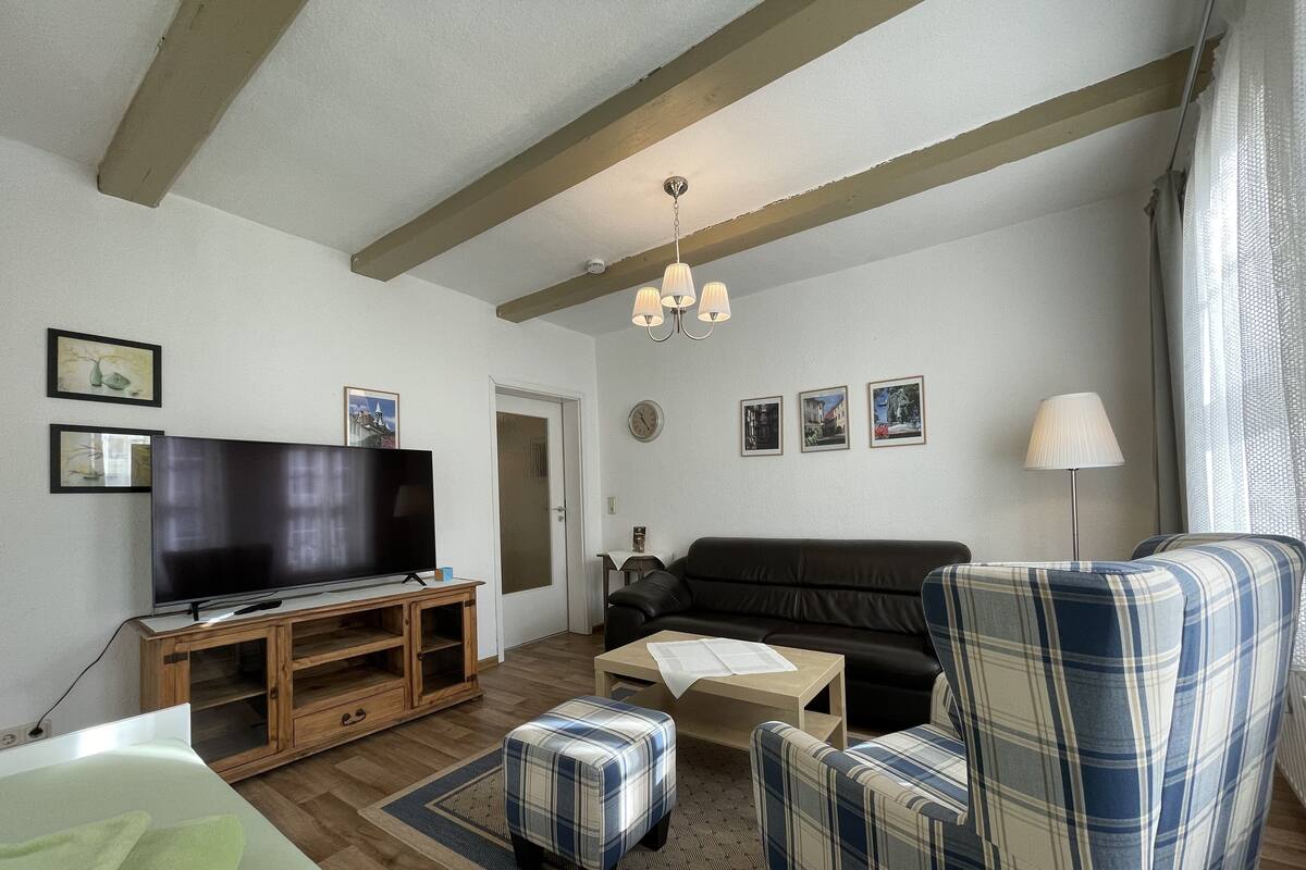 A living room with a television, sofa, ottoman, and a lamp.