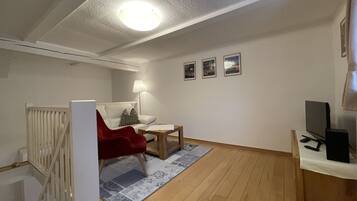 Un salon moderne avec un fauteuil rouge, une petite table, une lampe et un téléviseur.
