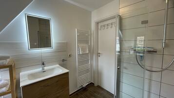 A modern bathroom with a shower, a sink, and a mirror.