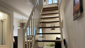 A staircase with wooden steps and white railings leading to a second floor. - Urlaub im Fachwerk (Quedlinburg)