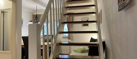 Una escalera de madera con barandillas blancas que lleva al segundo piso.
