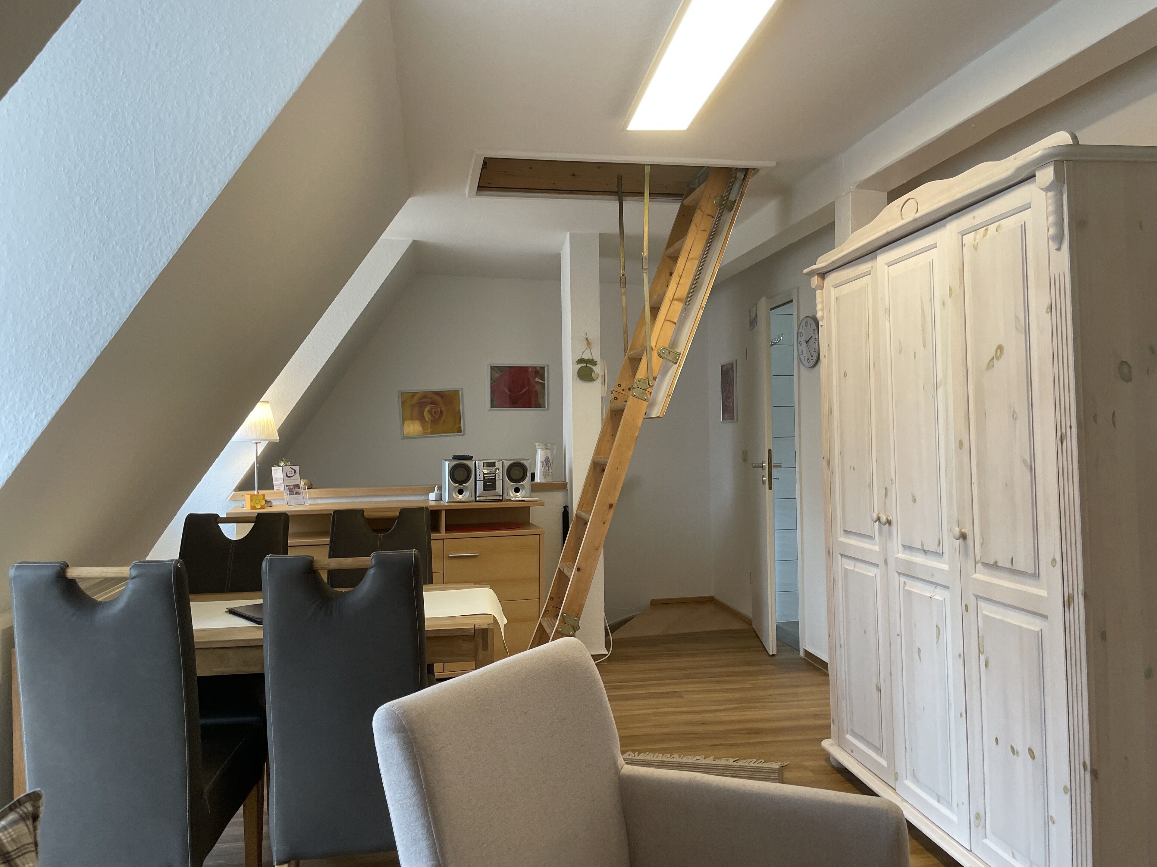 A loft-style room with a dining area, a staircase, and a wardrobe.