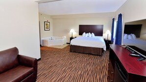 Habitación de hotel con una cama grande, baño privado con bañera, televisor de pantalla plana y escritorio con silla.