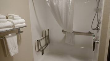 A shower with a glass door, a towel rack with folded towels, and a shower control panel.