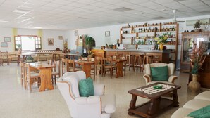 A spacious hotel lobby with a bar area, multiple seating arrangements, and a variety of decorative items. - Hotel Cesotta (Forio)