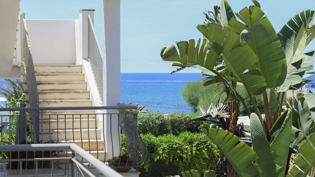 A balcony with a view of the sea, a staircase, and lush greenery. - Hotel Cesotta (Forio)