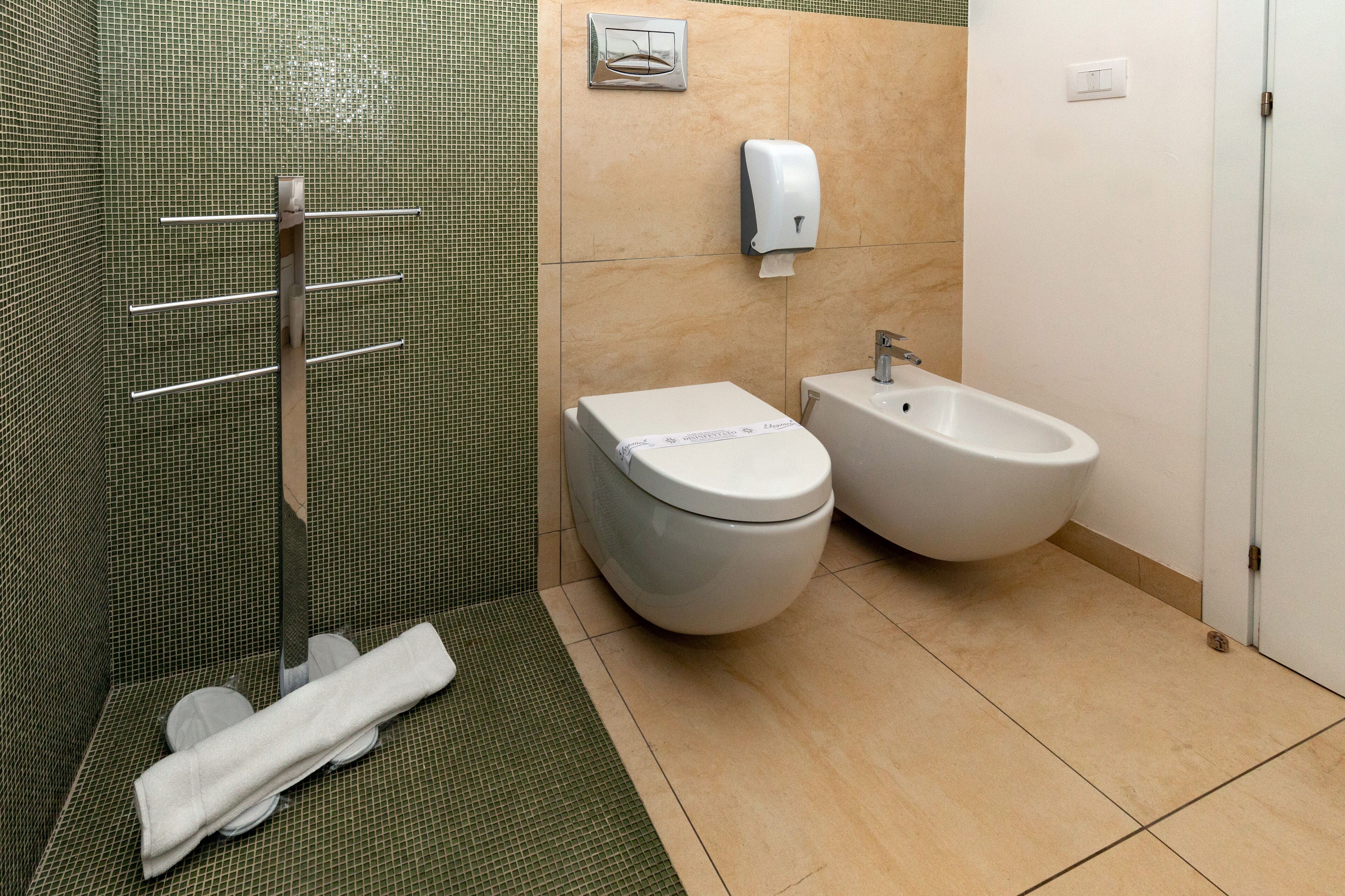 Een badkamer met een toilet, bidet en handdoekhouder.