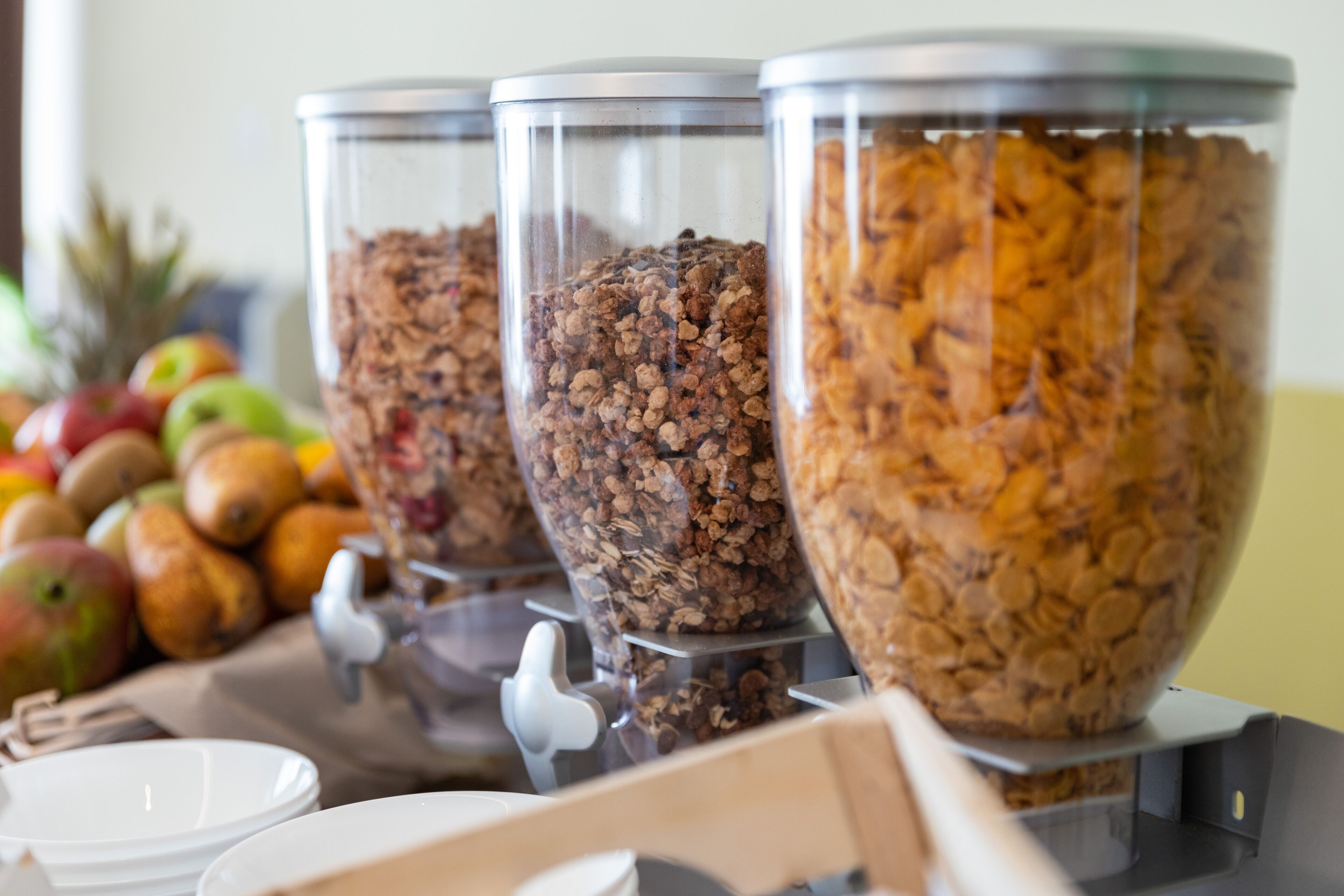 A breakfast buffet with various granola and cereal options in clear containers.