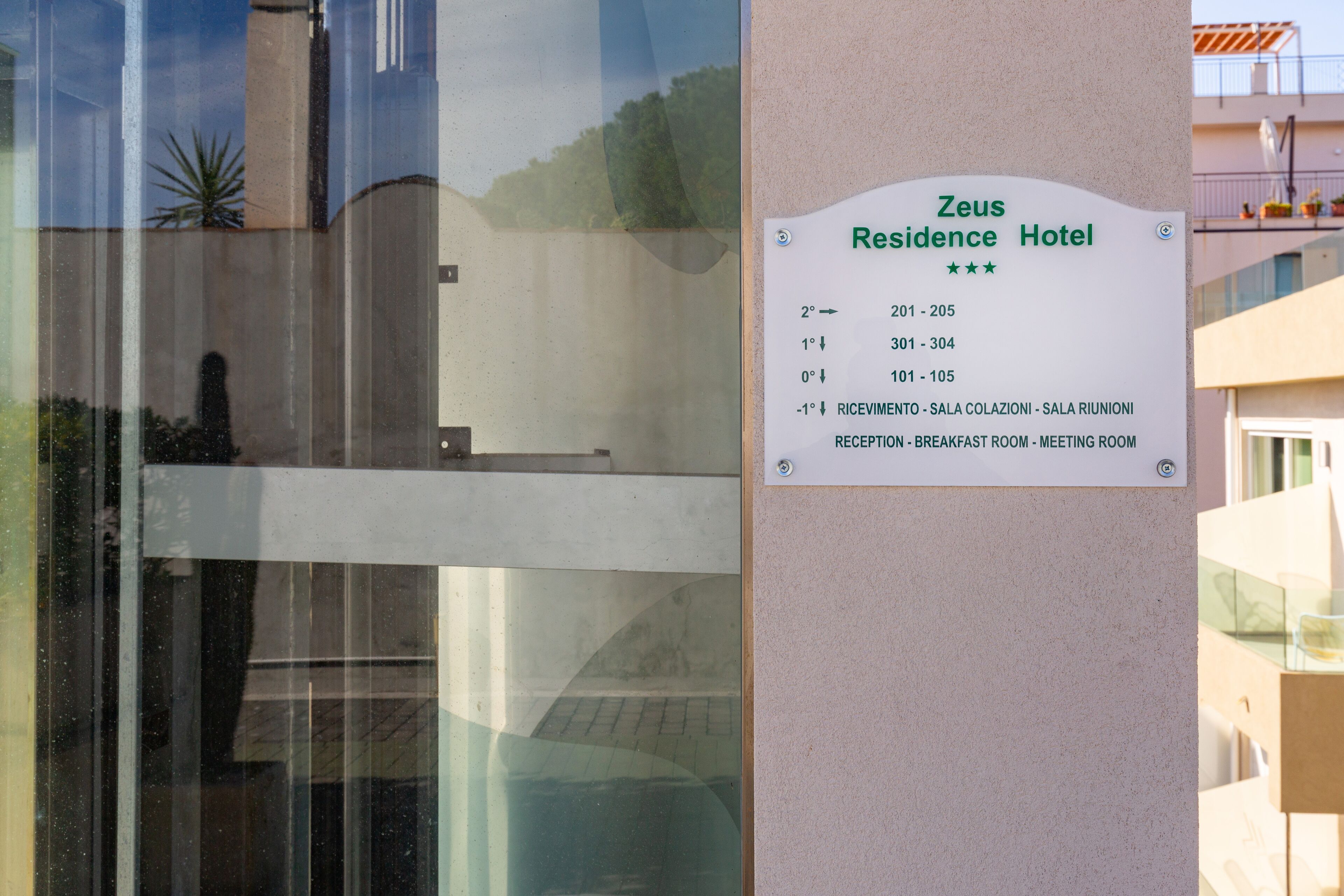Letrero del Hotel Zeus Residence con los números de habitación y los servicios enumerados.