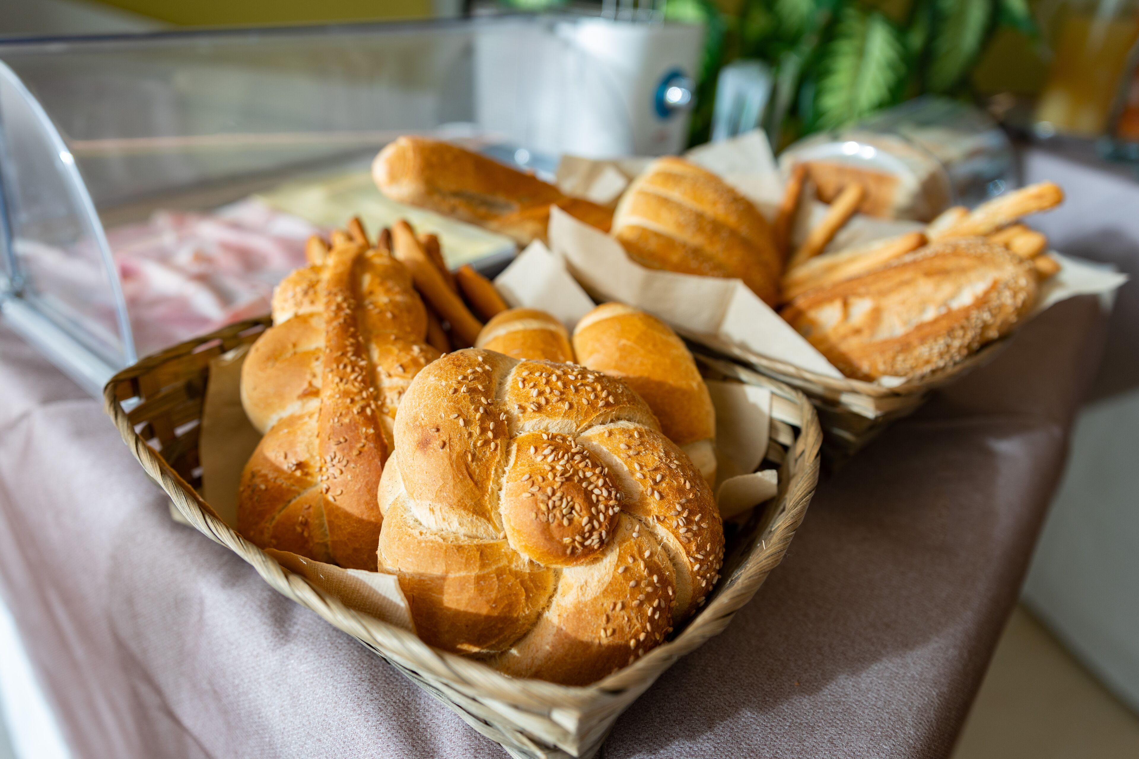 Una cesta con panes y pasteles sobre una mesa.
