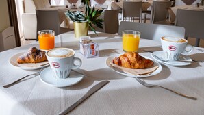 A breakfast setting with croissants, coffee, and orange juice on a table. - Zeus Residence Hotel (Aci Castello)