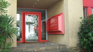 Entrada de un edificio con una puerta roja y buzón.