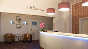 A reception area with a counter, two chairs, framed pictures on the wall, and a 'Willkommen' sign. - Acron Traben-Trarbach (Traben-Trarbach)