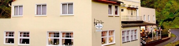 Un bâtiment à deux étages, doté de nombreuses fenêtres, d’une enseigne indiquant qu’il s’agit d’un pub, et d’un balcon avec des balustrades.