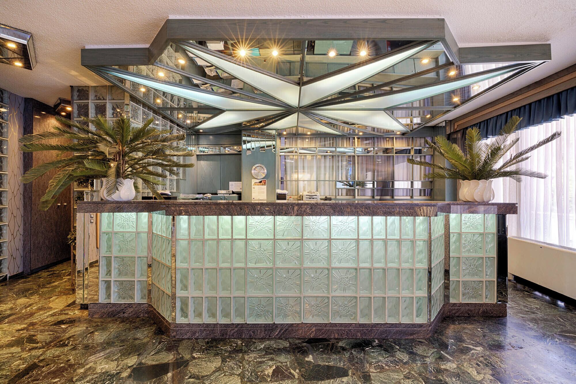 Un área de recepción con separador de vidrio, piso de mármol y un diseño moderno del techo.
