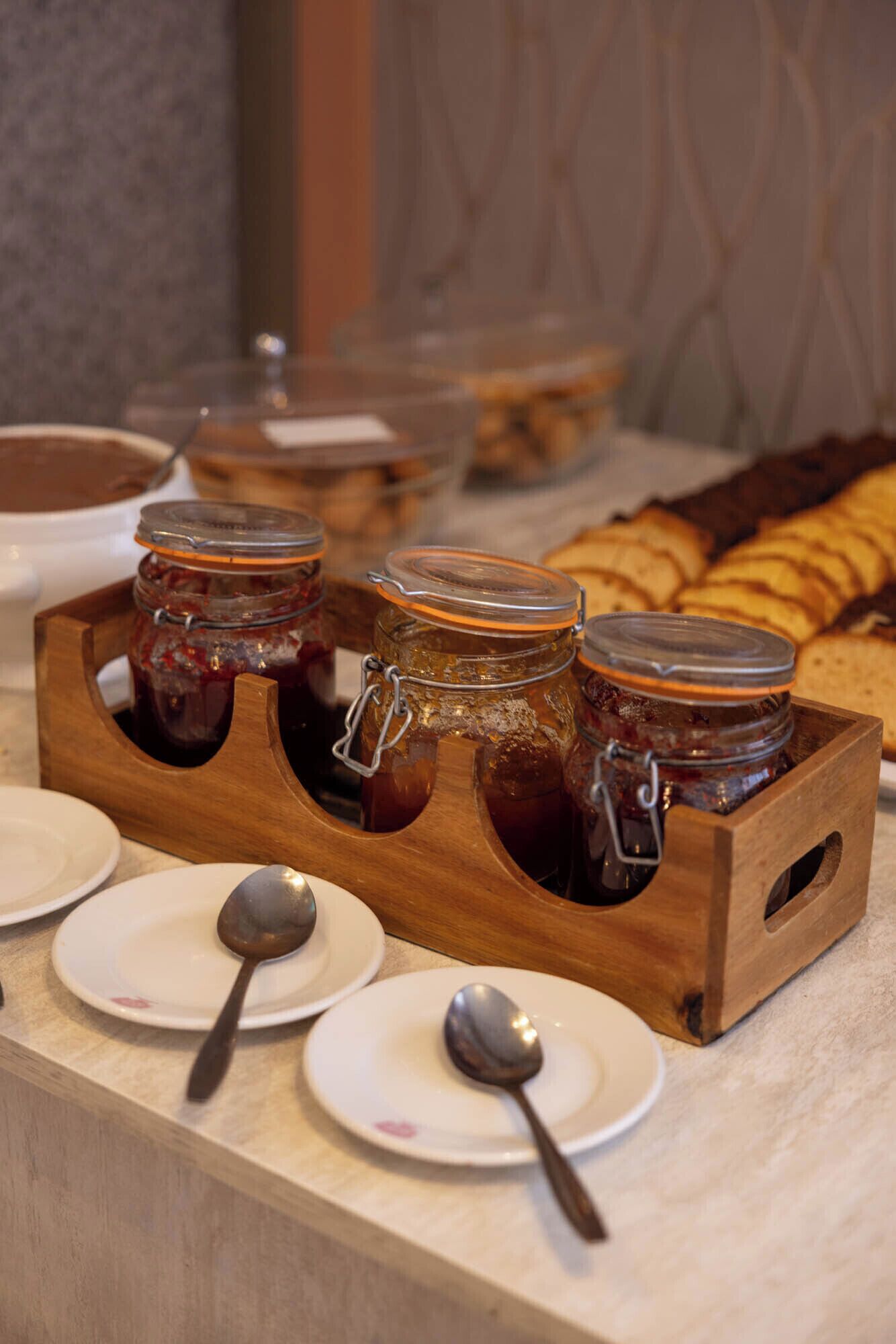 A breakfast buffet with jars of jam and bread.