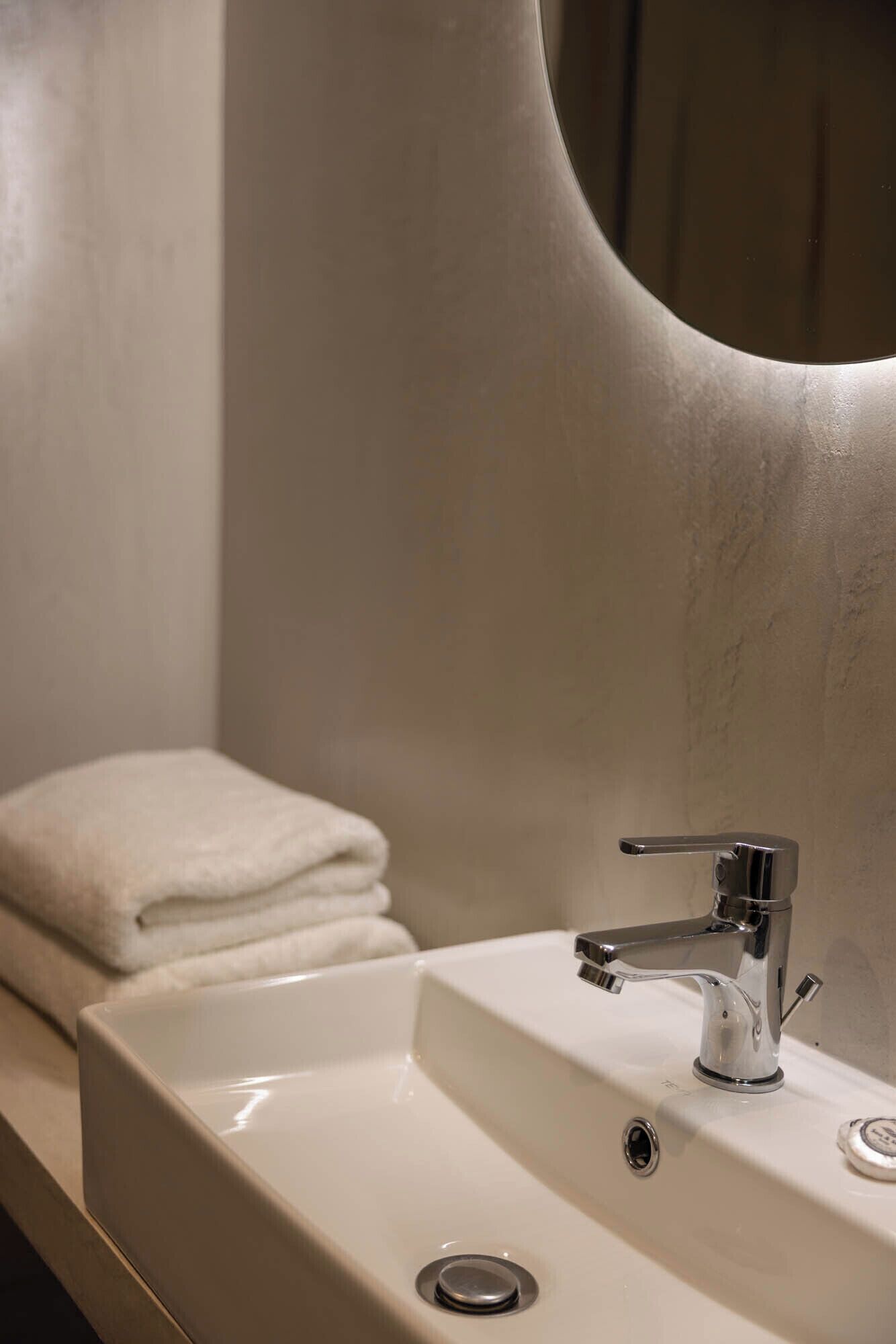 A bathroom sink with a chrome faucet, a mirror, and a towel on the counter.