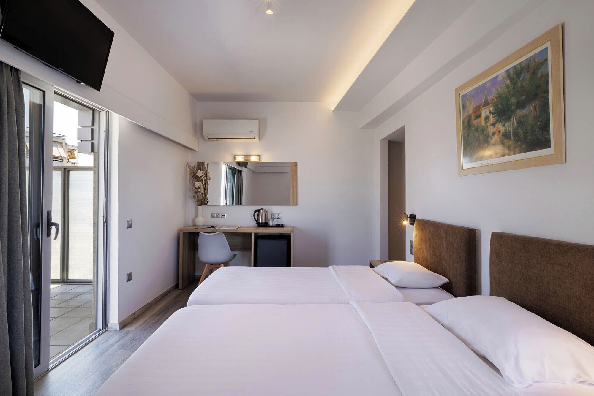 A hotel room with two beds, a desk, a chair, a mirror, and a painting on the wall.