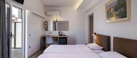 A hotel room with two beds, a desk, a chair, a mirror, and a painting on the wall.